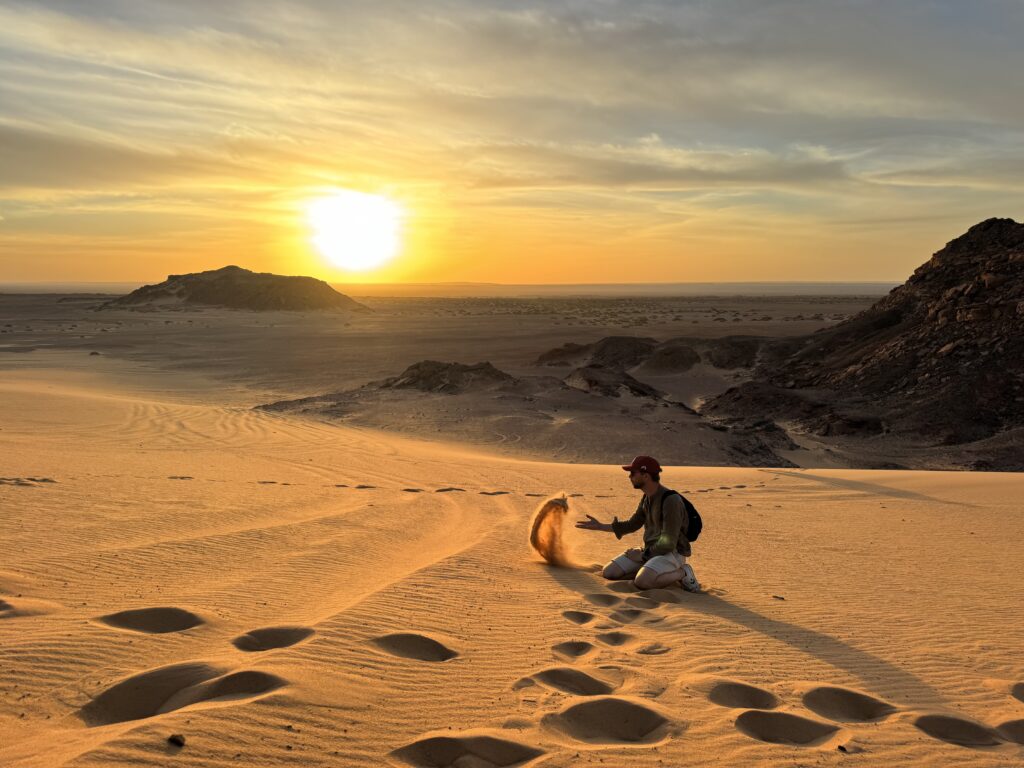 on voit des traces de pas d'un homme dans le désert qui s'arrête sur le sable sous un soleil d'une lumière intense. Un temps suspendu, une pause méditative.